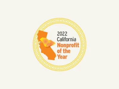 Circular badge with text "2022 California Nonprofit of the Year" and California map with an orange butterfly.
